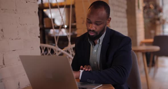 African Businessman Touches Smart Watch in Cafe