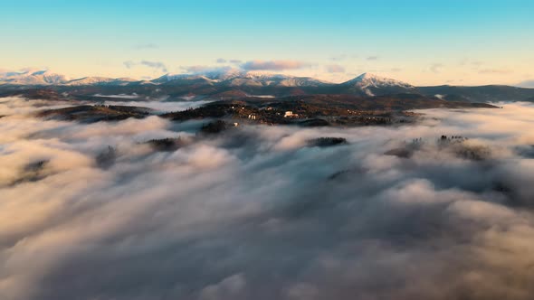 Aerial view of a small village houses on hill top in fall foggy mountains at sunrise. alt