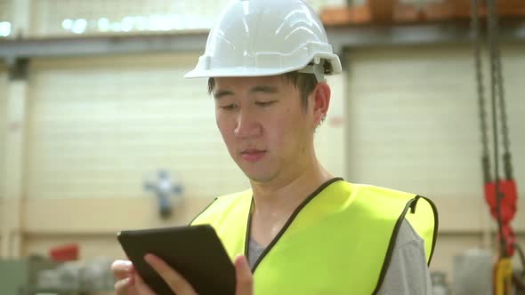 Young Asian Male Factory Worker Using a Digital Tablet