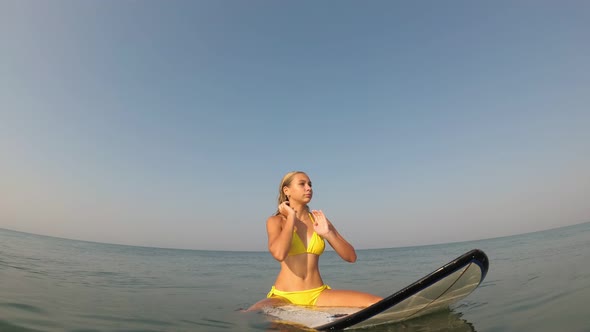 Young Sexy Woman Sits on a Surfboard in the Sea. Surfer Woman in the Sea