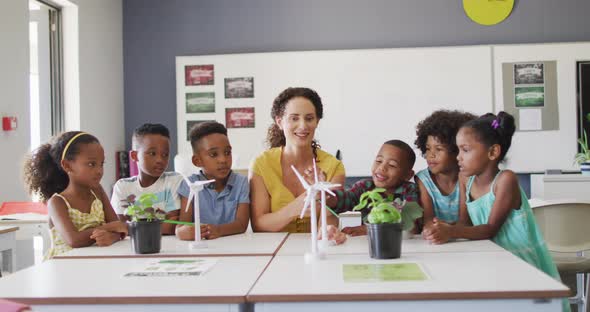 Video of happy caucasian female teacher and class of diverse pupils studying ecology in classroom