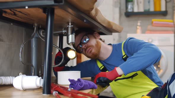 Portrait of Male Plumber Fitting Sink Pipe In Bathroom