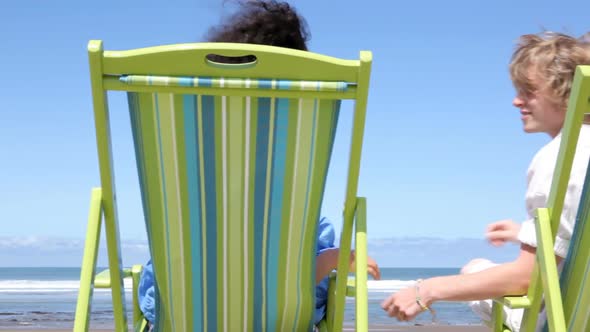 Couple sitting in chairs at beach kiss