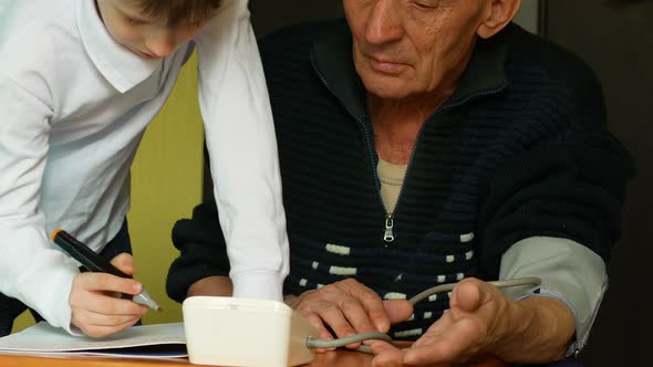 Caucasian pensioner over 70 measures blood pressure at home, grandson writes down pressure statistic