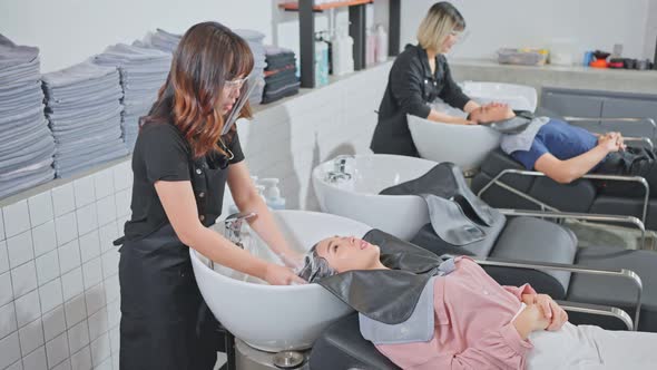 Asian young beautiful woman customer getting hair washed in hair beauty salon by hairdresser stylist