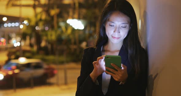 Business woman looking at mobile phone at night 