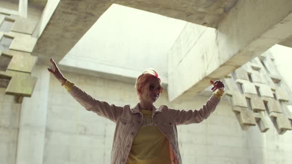 Woman with pink hair dances in an abandoned building