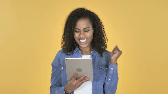 African Girl Excited for Success While Using Tablet Isolated on Yellow Background