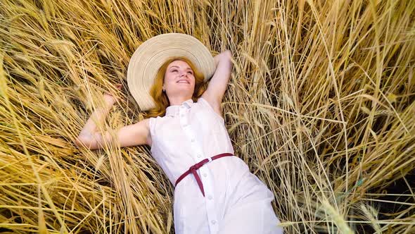 Camera Spin Over Young Red Haired Woman Lying on Wheat Field and Having Rest