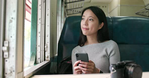 Woman looking at mobile phone and taking train