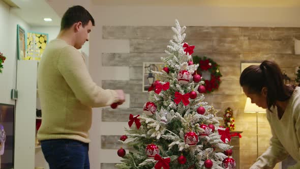 Caucasian Couple with Matching Clothes Decorate Christmas Tree