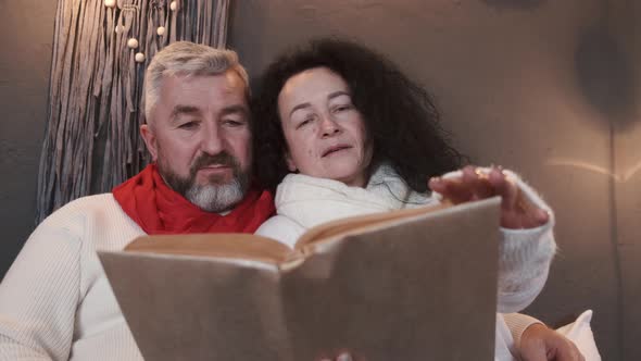 Senior Couple Reading and Relaxing on the Bed in Christmas Atmosphere