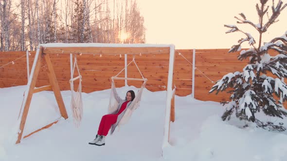 A Beautiful Woman Swings Cheerfully on a Swing in a Country Hunting House in Winter