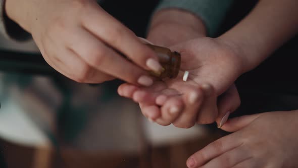 Woman Puts Small Medicine on Little Daughter Palm in Room