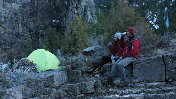 Couple sitting in camp as they drink with each other