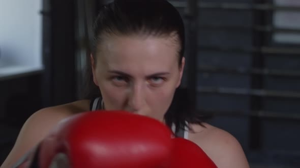 Female Boxer in Gloves Looking at Camera and Throwing Punches