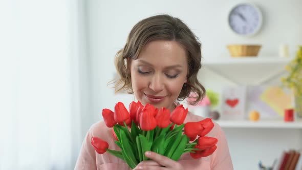 Young Beautiful Female Smiling Camera Holding Tulips in Hands, Spring Freshness