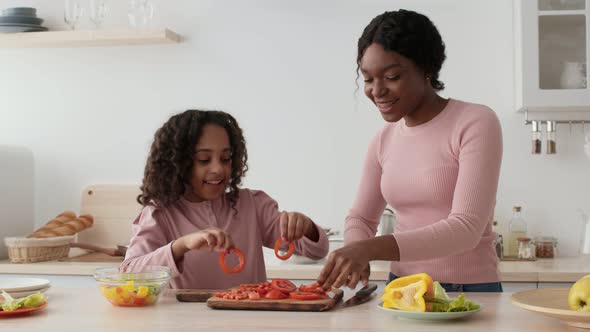 Happy African American Mother and Daughter Taking Slices of Tomato and Making Vegetable Glasses