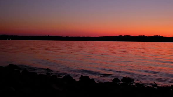 Dark scenic panning time lapse over a lake with waves coming into the shore at sunset