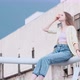 Young Beautiful Woman Sits on Balcony on Buildings Background and the Wind Blows Her Hair - VideoHive Item for Sale