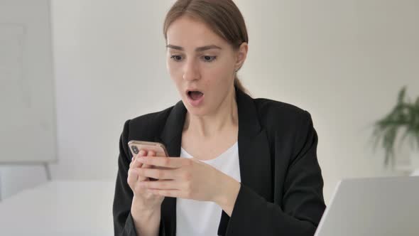 Shocked Young Businesswoman Using Smartphone