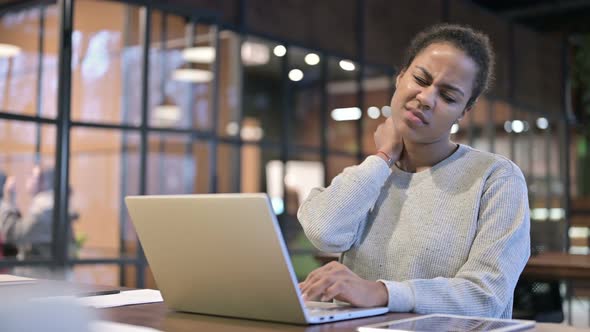 African Woman with Neck Pain Working on Laptop