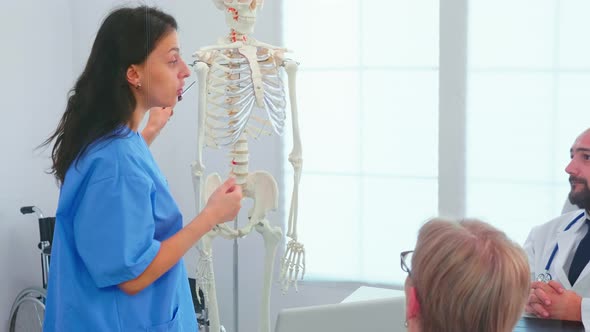 Female Nurse Demonstrating on Skeleton in Front of Medical Surgeons