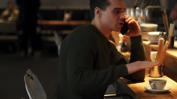 Positive man wearing sweater talking by phone