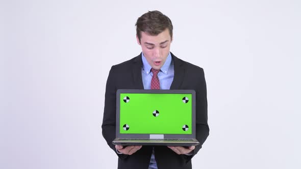 Young Happy Handsome Businessman Showing Laptop and Looking Surprised