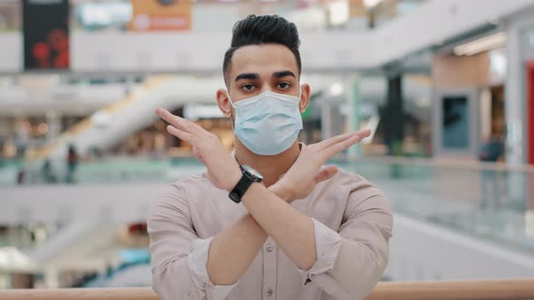 Young Hispanic Guy in Medical Mask Show Forbidding Gesture Serious Arab Man in Respirator Stand in