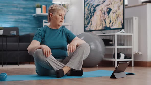 Aged Person Doing Physical Exercise and Watching Workout Video