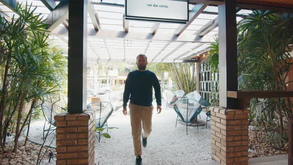 Man with Beard Walks and Enters in the Modern Cafe