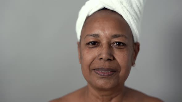 Senior african woman with facial cream smiling on camera during beauty day