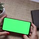 Woman holding smartphone with green screen and touch on screen. - VideoHive Item for Sale
