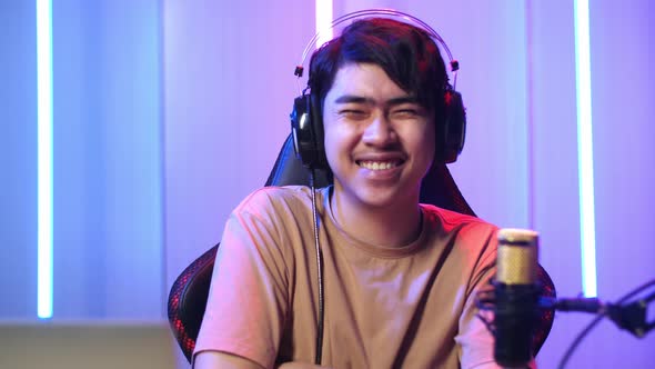 Asian Man Playing Video Game With Mobile Phone Then Smiles To Camera While Live Stream