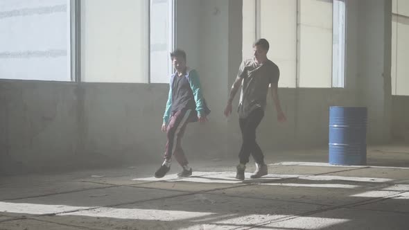 Two Friends of Successful Dancers Are Dancing Breakdance in an Abandoned Dusty Building