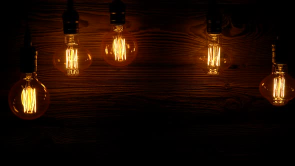 Five Retro Light Bulbs Slowly Light Up On A Wooden Background.