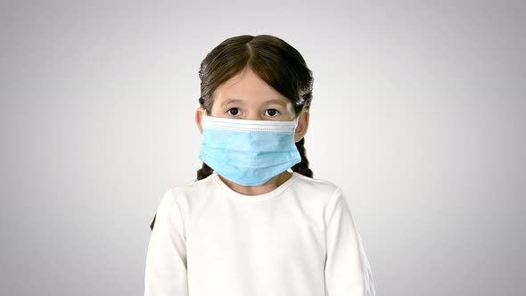 Little Girl Taking Her Face Mask Off and Smiling at Camera on Gradient Background