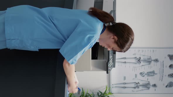 Vertical Video Portrait of Medical Assistant Talking to Receptionist at Hospital Reception Counter
