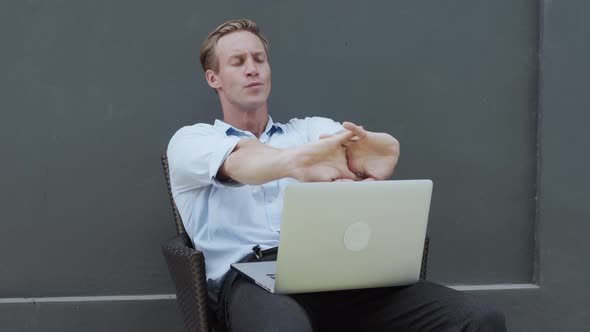 Man Works with Laptop Stretching Arms Relaxing Body Grey Wall on Background