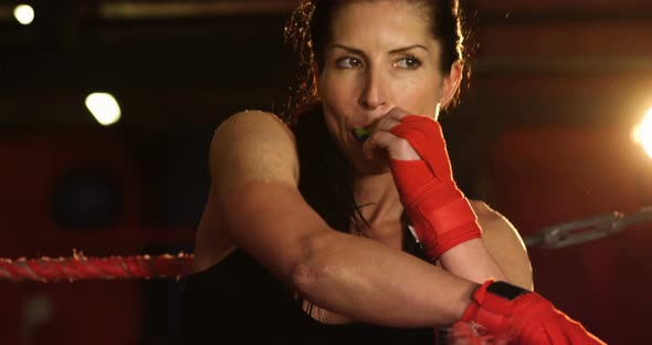 Tired female boxer standing in the ring