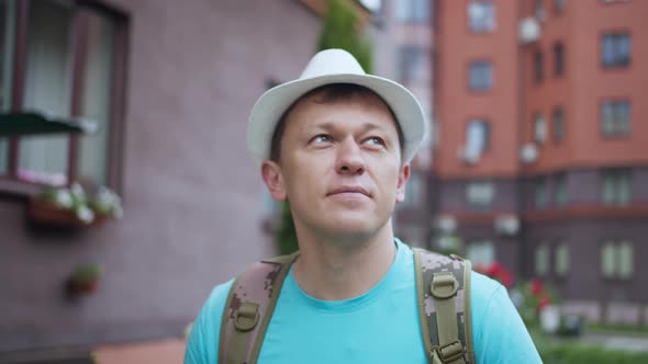 Portrait of a Male Tourist in a White Hat Walking Around the City Camera Tracking