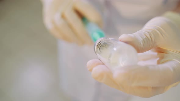 Medical worker in white gloves is preparing an injection.