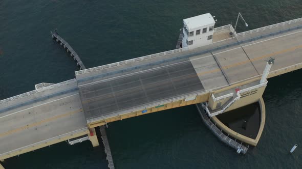 Aerial oribiting a bridge as it rises and a boat driving past