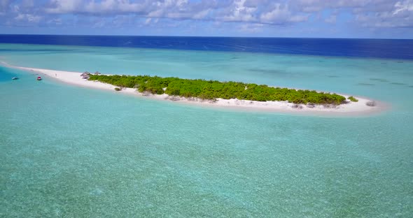 Daytime flying tourism shot of a sandy white paradise beach and turquoise sea background in colorful