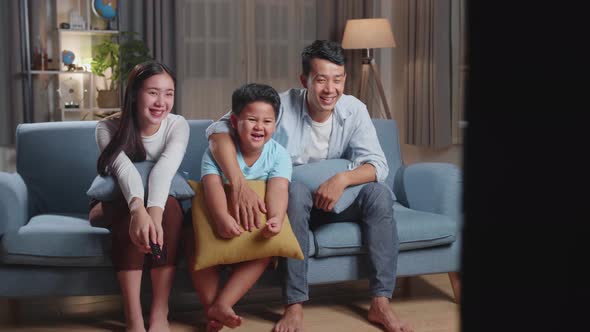 Asian Family, Leisure And People Concept - Happy Smiling Father, Mother And Son Watching Tv At Home