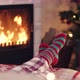 Woman feet in christmas woolen socks near fireplace decorated tree tee cup in backg - VideoHive Item for Sale