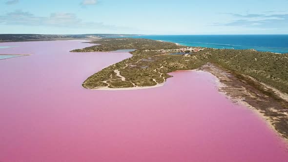 Aerial wide shot, large pink water lagoon, blue ocean in background