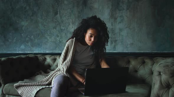 Young Attractive AfricanAmerican Woman Using Laptop Computer Sitting on Sofa at Home