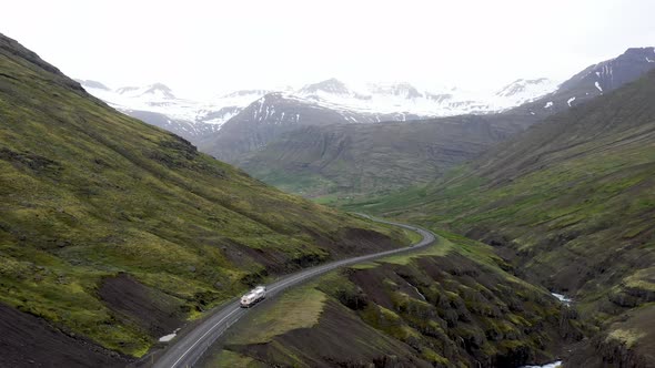 Semi truck driving through mountains in Iceland with drone video moving behind.